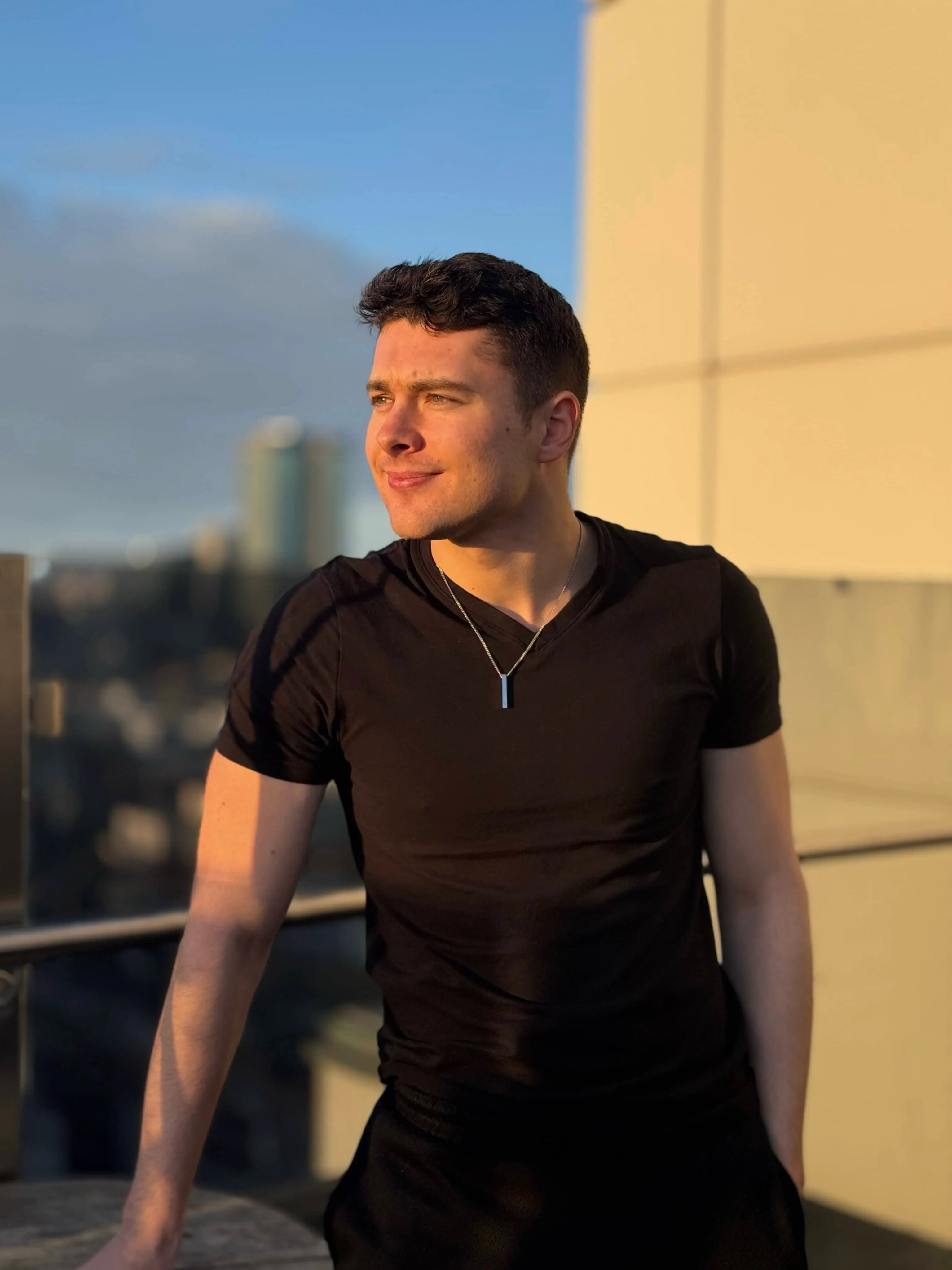 Tommy leaning against a railing with city view